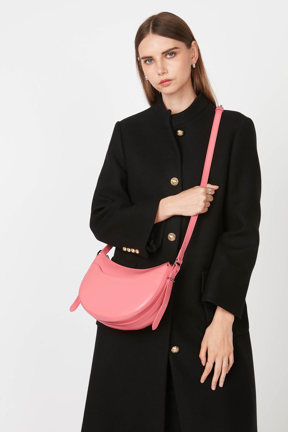 Lancaster besace Suave Ace rose portée en bandoulière avec un long manteau noir.