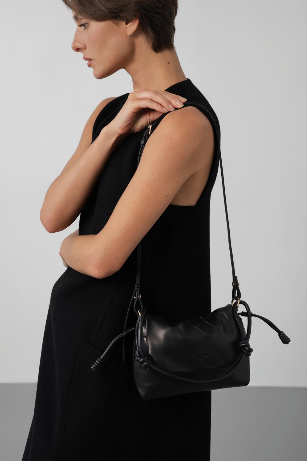 Lancaster besace Lush noire portée à l’épaule avec une robe noire sans manches.